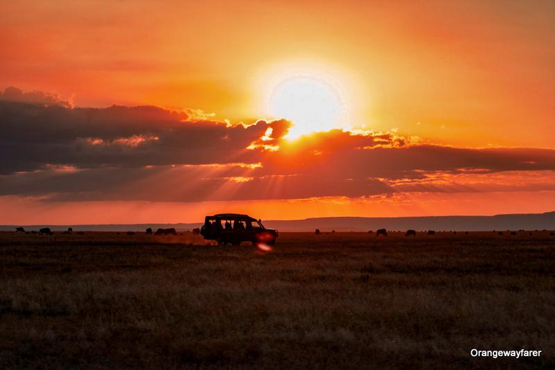 A safari jeep awaits on the African Savannah as the Sun sets at the background!