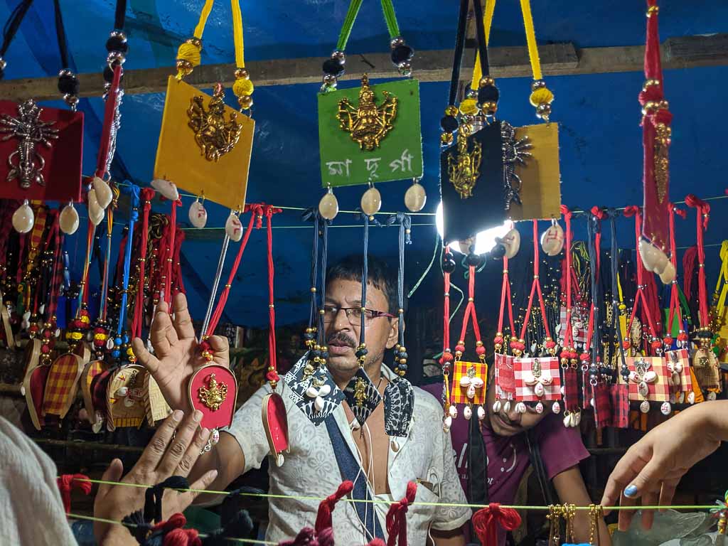 A man selling handcrafted jewelry at the entrance of Tridhara